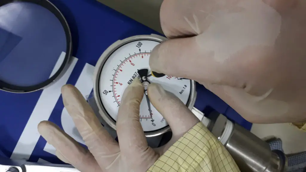 Holding the pressure gauge needle while rotating the screw